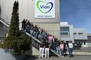 Personengruppe vor Gebäude mit Aufschrift Vion