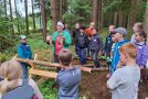 Eine Gruppe Kinder steht mit einer Erwachsenen im Wald