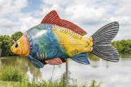 Bunte Karpfenskulptur vor einem Teich